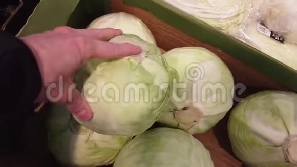 在蔬菜商店或市场上选择卷心菜的手视频的预览图