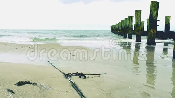 锚绳在沙滩沙中丢失带海水的破堤木杆视频的预览图