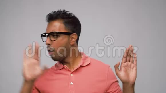 戴眼镜的印度男人在灰色背景下跳舞视频的预览图