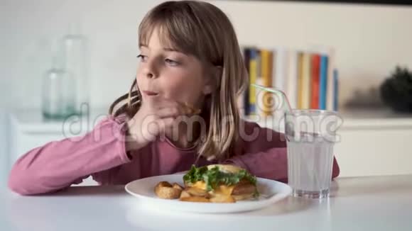 无聊的小女孩一边看一边在家吃着满是土豆的汉堡视频的预览图