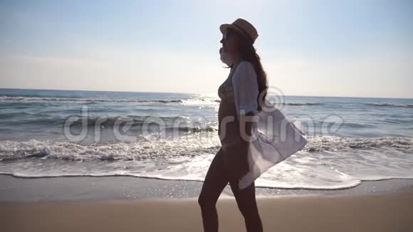 穿比基尼和衬衫的快乐女人在海边散步年轻漂亮的戴帽子的女孩享受生活视频的预览图