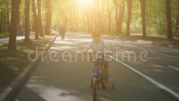 在柏油路骑自行车的快乐男孩可爱的男孩在自行车道上学骑自行车视频的预览图