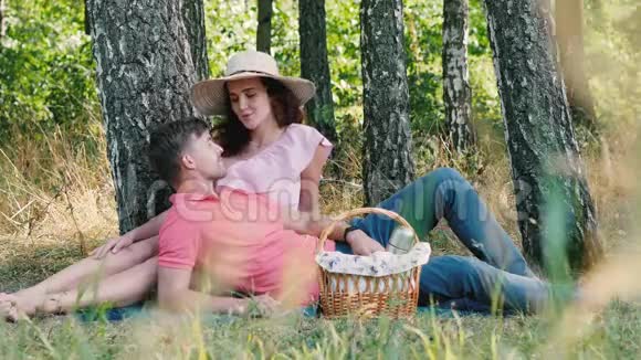浪漫的野餐时间快乐的年轻夫妇接吻男人趴在她的手上公园的户外活动视频的预览图