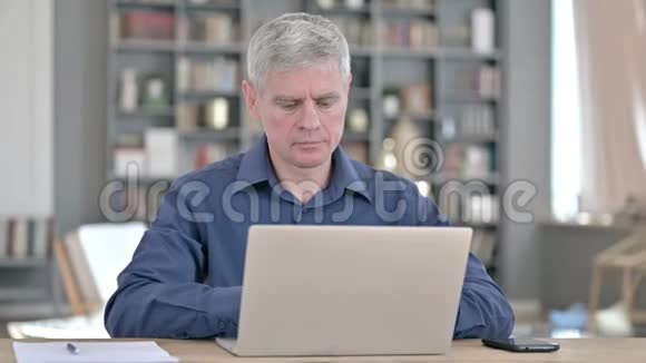疲惫的中年男子在笔记本电脑上工作时背痛视频的预览图