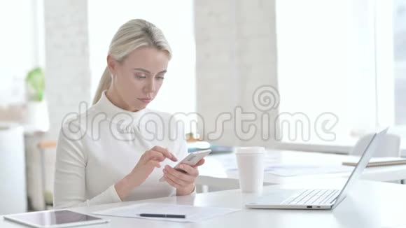 失望的年轻女商人在办公室使用智能手机视频的预览图