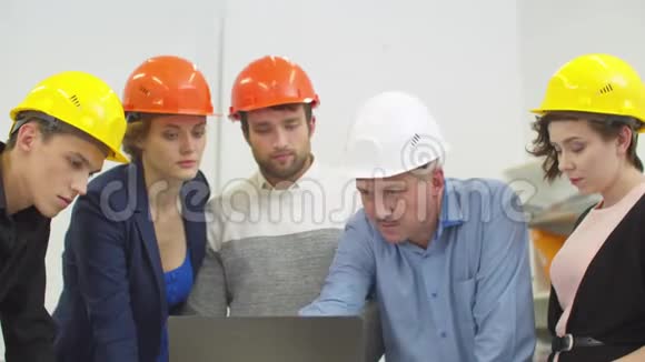 戴着头盔的同事站着听说话的人说话他在笔记本上显示了一些东西视频的预览图