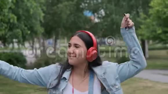 戴着红耳机的快乐美丽女孩跳过音乐视频的预览图