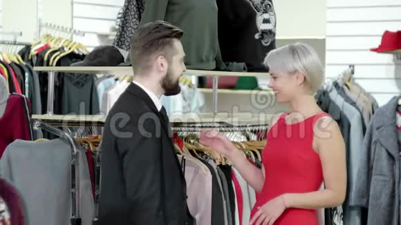 挑选新衣服快乐迷人美丽微笑快乐的成年夫妇在店里挑选新衣服视频的预览图