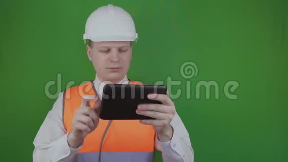 电子平板电脑工程师铬化白色头盔和橙色反光背心或视频的预览图