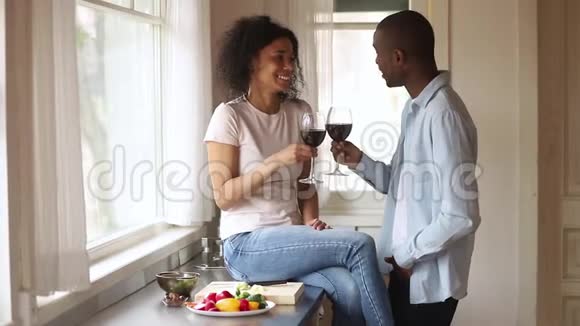 快乐的非洲夫妇碰杯谈笑风生厨房视频的预览图