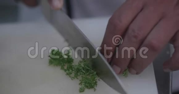 在餐厅的厨房里男人的手在切新鲜的欧芹视频的预览图
