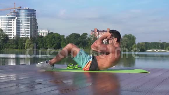 在瑜伽垫上做腹部按摩的帅哥健身模特视频的预览图