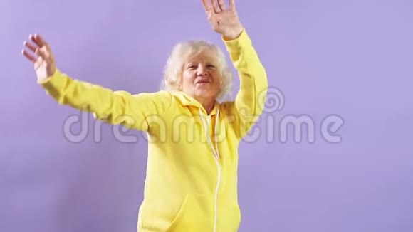 慢动作一位老年妇女在演播室里听音乐和舞蹈视频的预览图