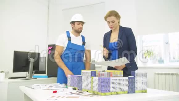 女人和建筑工人站在一起展示一些房子模型视频的预览图