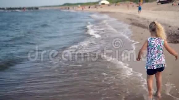 快乐的女孩在海浪中奔跑溅起水花有趣的女孩很开心视频的预览图