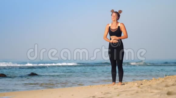 美丽的女孩在阳光明媚的海滩上做普拉纳亚马运动视频的预览图
