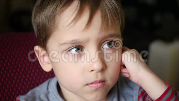 一个可爱的小男孩的肖像有一个深思熟虑的样子这孩子看动画片视频的预览图