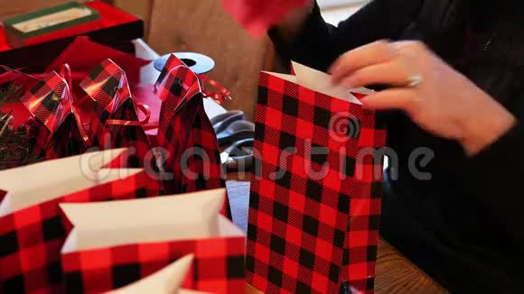 奶奶的手用打孔机和剪刀把红色的节日礼品袋装上再加上一条小丝带视频的预览图