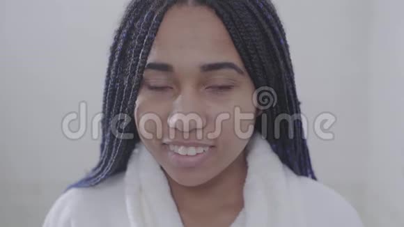 正面非洲裔美国妇女的肖像带着可怕的目光看着相机微笑穿白衣服的漂亮少年视频的预览图