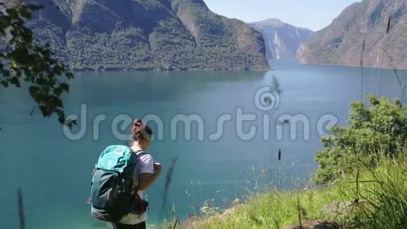 年轻女子背着一个大背包走在山的边缘视频的预览图