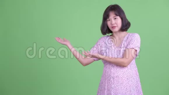 快乐的亚洲孕妇一边说话一边展示东西视频的预览图