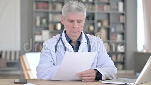 职业中年医生在办公室阅读文件视频的预览图