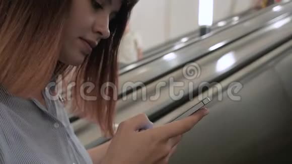 女人从地下地铁自动扶梯上站起来使用智能手机应用程序视频的预览图