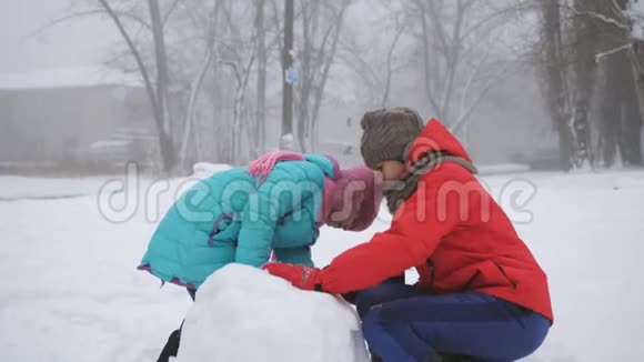 冬季运动会两个姐姐在冬天户外堆雪人视频的预览图