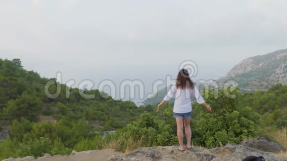 年轻女子站在山顶上举手视频的预览图