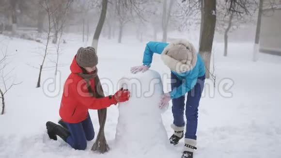 母女一个少年在院子里堆雪人视频的预览图