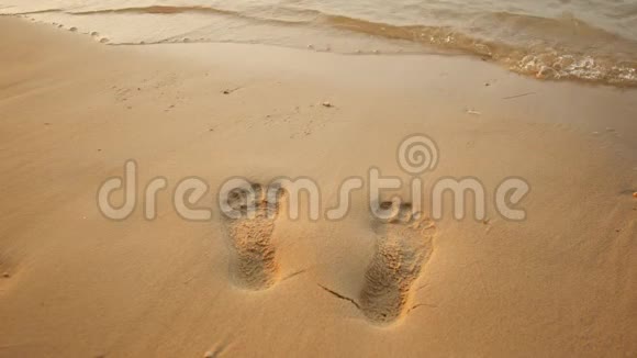光秃秃的沙滩上的人类脚印被海浪冲走了视频的预览图