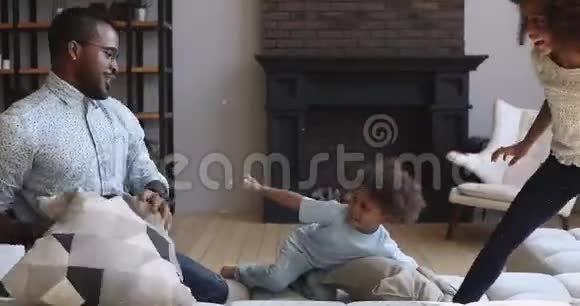 免费的非洲爸爸和孩子在沙发上打枕头战视频的预览图