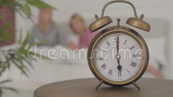 一个老式闹钟的特写显示在下午6点两个金发白种人女人在它后面睡觉女孩视频的预览图