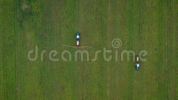 两台拖拉机相互驾驶的空中视野并在油菜田上喷洒化肥视频的预览图