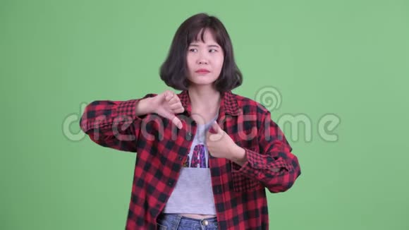 惑乱的亚洲时髦女人在拇指向上和拇指向下之间做出选择视频的预览图