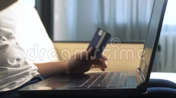 女孩用笔记本电脑数字平板电脑制作网上销售购物概念黑发女人躺在沙发上看网上商店视频的预览图