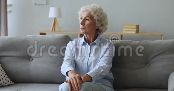 一位体贴的老妇人把目光移开想坐在沙发上视频的预览图