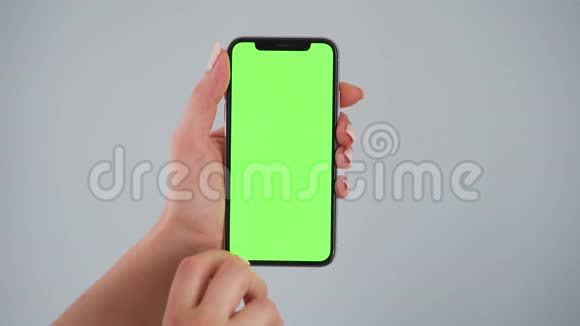 女性手使用智能手机绿色屏幕在灰色背景铬键视频的预览图