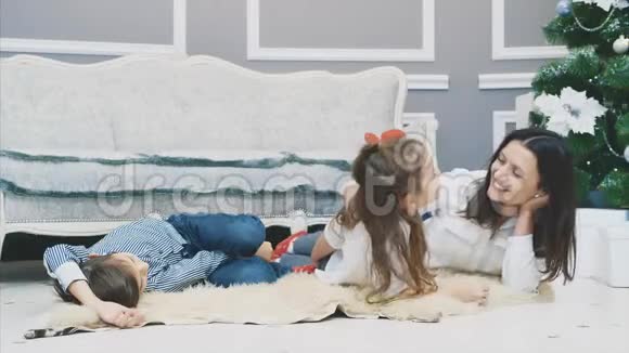小女孩和男孩和他们的母亲坐在冷杉附近的毛皮地毯上一起享受时光视频的预览图