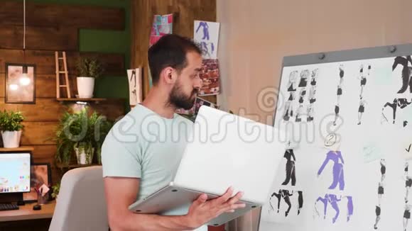 年轻的创意总监拿着他的笔记本电脑坐在办公室里视频的预览图