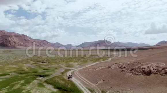 在4x4路的高空汽车沿着干旱的沙漠山脉上的砾石小径行驶帕米尔公路丝绸之路旅行视频的预览图