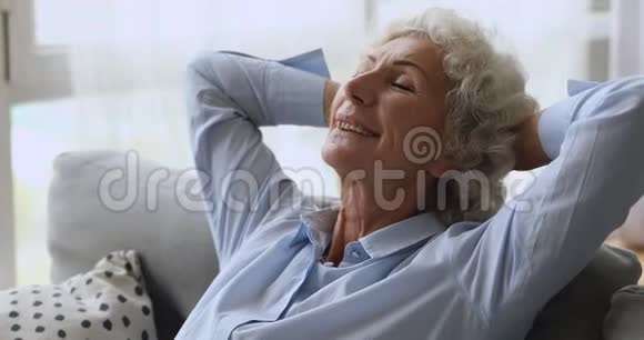 快乐轻松的老妇人闭着眼睛躺在沙发上视频的预览图