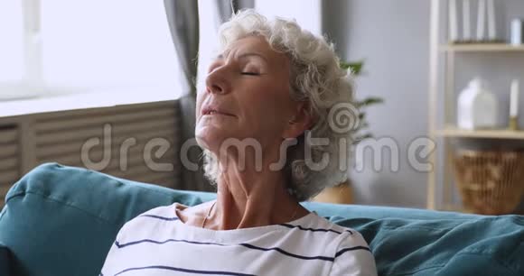 平静的老人放松呼吸沙发上的新鲜空气视频的预览图