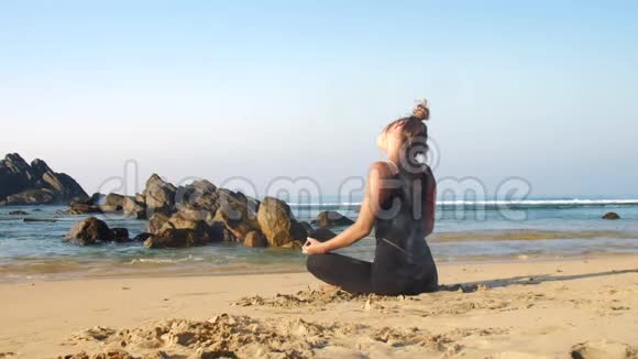 运动女孩伸展脖子在蓝色海洋与棕色岩石视频的预览图