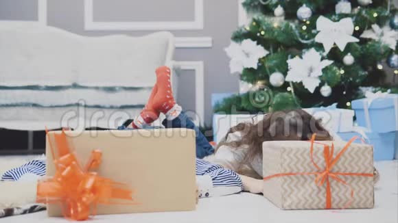 无忧无虑微笑着的小兄弟姐妹享受着圣诞节的时光躺在冷杉下的地毯上露出头来视频的预览图