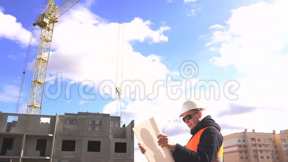一位白种人的男工程师是一位穿着信号背心和头盔的设计师他正在研究建造一个建筑计划视频的预览图