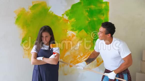 年轻的家庭在新公寓里修理在公寓里画了一堵墙一男一女在修房子视频的预览图
