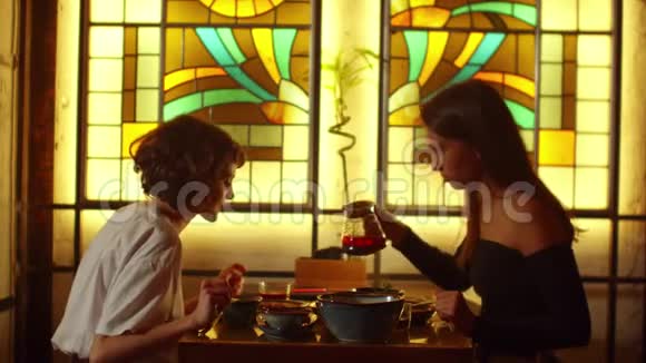 慢动作女人坐在咖啡馆的桌子旁女孩倒茶在杯子里另一个女孩说话视频的预览图