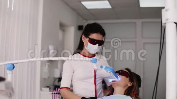 牙科诊所牙齿美白的程序戴防护眼镜的年轻女子坐在牙医椅上医生视频的预览图