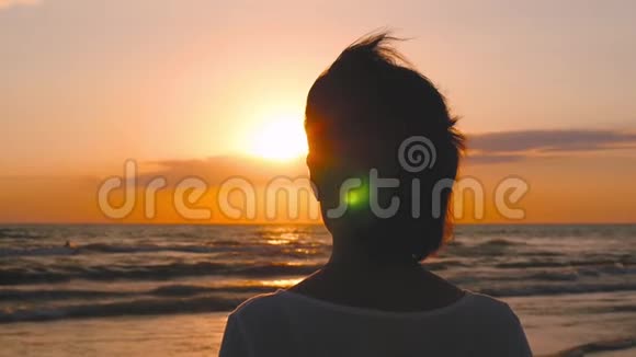 日落时站在海边朝地平线看的女孩的剪影视频的预览图